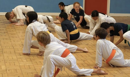 Children at marston karate class stretching in a busy class, book now to join them