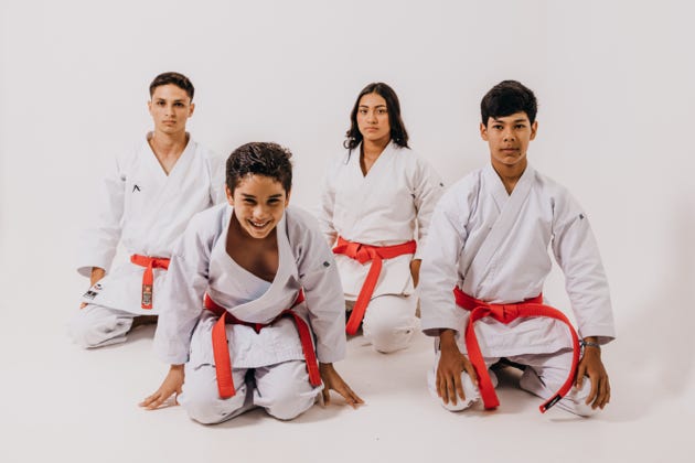 Family of 4 looking happy in karate uniforms